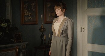 Movie still from “House of Tolerance” (2011), directed by Bertrand Bonello – A woman standing in front of a wall with a candle; Medium shot, Over the shoulder angle