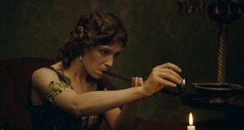 Movie still from “House of Tolerance” (2011), directed by Bertrand Bonello – A woman is holding a bottle of wine and smoking a pipe; Close Up shot, Low angle