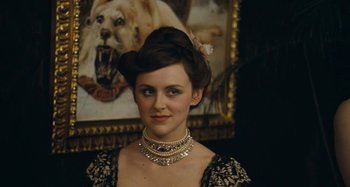 Movie still from “House of Tolerance” (2011), directed by Bertrand Bonello – A woman in a black and white dress with a dog in the background; Close Up shot, Over the shoulder angle