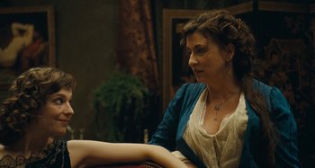 Movie still from “House of Tolerance” (2011), directed by Bertrand Bonello – A woman sitting next to another woman on a chair; Medium shot, Over the shoulder angle