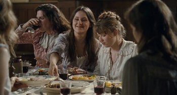 Movie still from “House of Tolerance” (2011), directed by Bertrand Bonello – A group of people sitting at a dinner table; Medium shot, Over the shoulder angle
