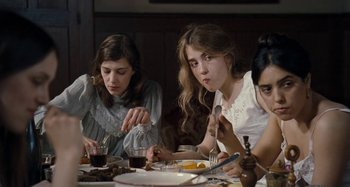Movie still from “House of Tolerance” (2011), directed by Bertrand Bonello – A group of people sitting at a dinner table; Medium shot, Low angle