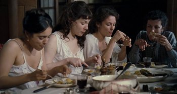 Movie still from “House of Tolerance” (2011), directed by Bertrand Bonello – A group of people sitting at a dinner table eating food; Medium shot, High angle