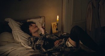Movie still from “House of Tolerance” (2011), directed by Bertrand Bonello – A woman laying in bed with a lit candle; Medium shot, High angle