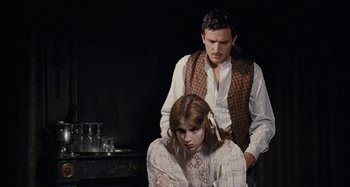 Movie still from “House of Tolerance” (2011), directed by Bertrand Bonello – A man and a woman sitting next to each other in front of a wall; Medium shot, Over the shoulder angle