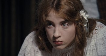 Movie still from “House of Tolerance” (2011), directed by Bertrand Bonello – A young woman in a white dress looking at the camera; Close Up shot, High angle
