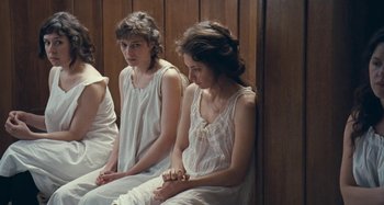 Movie still from “House of Tolerance” (2011), directed by Bertrand Bonello – Two women in white nightgowns sitting on a bench; Medium shot, High angle