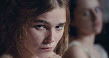 Movie still from “House of Tolerance” (2011), directed by Bertrand Bonello – A woman's face looking at the camera; Close Up shot, Over the shoulder angle