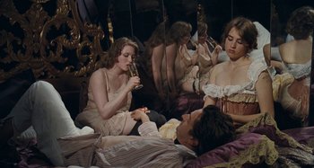 Movie still from “House of Tolerance” (2011), directed by Bertrand Bonello – A group of people sitting on top of a bed next to each other; Medium shot, High angle