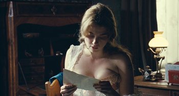Movie still from “House of Tolerance” (2011), directed by Bertrand Bonello – A woman in a white dress looking at a piece of paper; Close Up shot, High angle