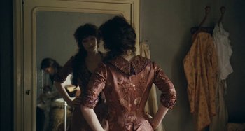 Movie still from “House of Tolerance” (2011), directed by Bertrand Bonello – A woman is standing in front of a mirror; Medium shot, Over the shoulder angle