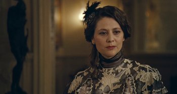 Movie still from “House of Tolerance” (2011), directed by Bertrand Bonello – A woman in a dress with a feather in her hair; Close Up shot, Over the shoulder angle