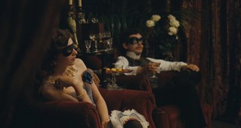Movie still from “House of Tolerance” (2011), directed by Bertrand Bonello – A man and a woman sitting on a red chair; Medium shot, Over the shoulder angle