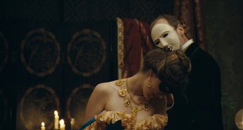 Movie still from “House of Tolerance” (2011), directed by Bertrand Bonello – A man and a woman wearing masks in front of a wall; Medium shot, Over the shoulder angle