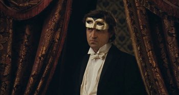 Movie still from “House of Tolerance” (2011), directed by Bertrand Bonello – A man in a tuxedo wearing a gold mask; Medium shot, Low angle