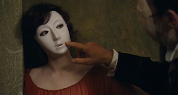 Movie still from “House of Tolerance” (2011), directed by Bertrand Bonello – A person with a mask touching a woman's face; Close Up shot, Over the shoulder angle