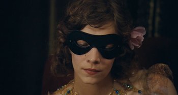 Movie still from “House of Tolerance” (2011), directed by Bertrand Bonello – A woman wearing a black mask with a flower in her hair; Close Up shot, High angle