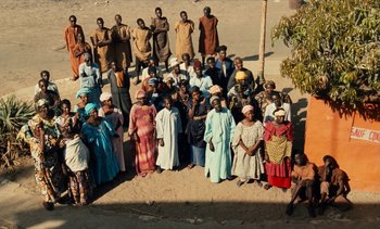 Movie still from “Hyenas” (1992), directed by Djibril Diop Mambéty – A large group of people standing together in a field; Extreme Wide shot, High angle