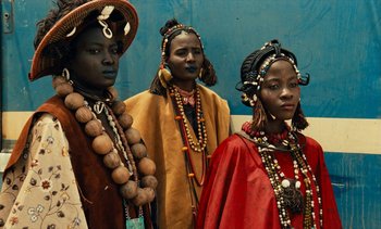 Movie still from “Hyenas” (1992), directed by Djibril Diop Mambéty – A group of people standing next to each other; Medium shot, Low angle