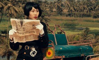 Movie still from “Hyenas” (1992), directed by Djibril Diop Mambéty – A woman in a black dress holding a newspaper; Close Up shot, High angle