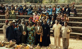 Movie still from “Hyenas” (1992), directed by Djibril Diop Mambéty – A group of men and women standing in front of fruit; Extreme Wide shot, High angle