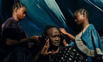 Movie still from “Hyenas” (1992), directed by Djibril Diop Mambéty – A group of people that are standing in a room; Medium shot, High angle