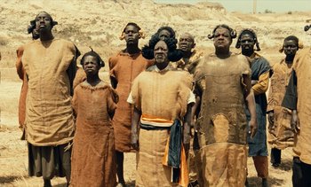 Movie still from “Hyenas” (1992), directed by Djibril Diop Mambéty – A group of people standing next to each other; Medium shot, High angle
