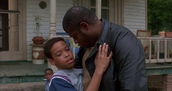Movie still from “Jason's Lyric” (1994), directed by Doug McHenry – A man and a boy standing next to each other on a porch; Medium shot, Over the shoulder angle