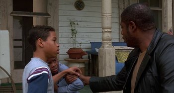 Movie still from “Jason's Lyric” (1994), directed by Doug McHenry – A group of young men sitting on the porch of a house; Medium shot, Over the shoulder angle