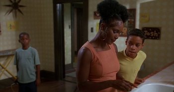 Movie still from “Jason's Lyric” (1994), directed by Doug McHenry – A woman and a boy standing next to each other in a room; Medium shot, Over the shoulder angle