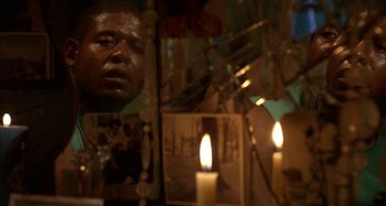 Movie still from “Jason's Lyric” (1994), directed by Doug McHenry – A man is reflected in a mirror with candles in front of him; Extreme Close Up shot, Low angle