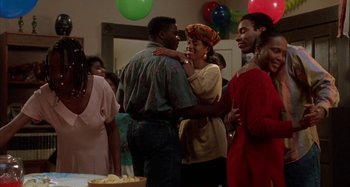 Movie still from “Jason's Lyric” (1994), directed by Doug McHenry – A group of people gathered at a birthday party; Medium shot, Over the shoulder angle