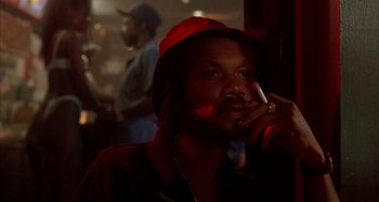 Movie still from “Jason's Lyric” (1994), directed by Doug McHenry – A man smoking a cigarette while wearing a red hat; Close Up shot, Low angle