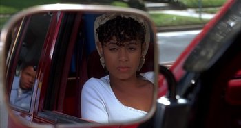 Movie still from “Jason's Lyric” (1994), directed by Doug McHenry – A woman sitting in the passenger seat of a car looking into a mirror; Close Up shot, Over the shoulder angle