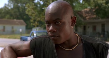 Movie still from “Jason's Lyric” (1994), directed by Doug McHenry – A bald man with a gold chain around his neck; Close Up shot, Low angle