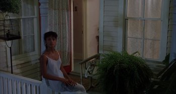 Movie still from “Jason's Lyric” (1994), directed by Doug McHenry – A woman sitting on a chair in front of a house; Medium shot, High angle