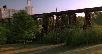 Movie still from “Jason's Lyric” (1994), directed by Doug McHenry – A person standing on a bridge over a river; Extreme Wide shot, Low angle