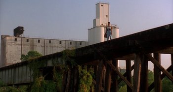 Movie still from “Jason's Lyric” (1994), directed by Doug McHenry – A man standing on top of a bridge near a grain silo; Extreme Wide shot, Low angle
