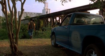 Movie still from “Jason's Lyric” (1994), directed by Doug McHenry – A man walking across a bridge next to a blue truck; Wide shot, Low angle