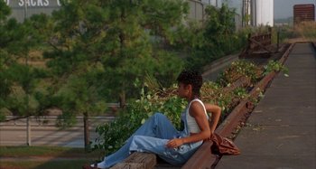Movie still from “Jason's Lyric” (1994), directed by Doug McHenry – A woman sitting on top of a tree branch; Wide shot, High angle