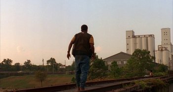 Movie still from “Jason's Lyric” (1994), directed by Doug McHenry – A man is walking on the train tracks; Wide shot, Low angle