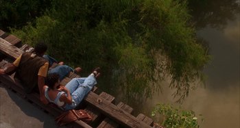 Movie still from “Jason's Lyric” (1994), directed by Doug McHenry – A man and a woman sitting on a wooden bridge; Wide shot, Overhead angle