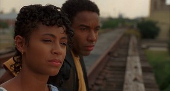 Movie still from “Jason's Lyric” (1994), directed by Doug McHenry – A man and a woman standing next to each other on train tracks; Close Up shot, Over the shoulder angle