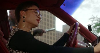 Movie still from “Jason's Lyric” (1994), directed by Doug McHenry – A woman driving a car with a cell phone in her hand; Close Up shot, Low angle
