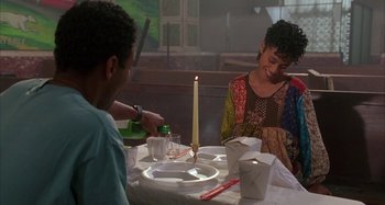 Movie still from “Jason's Lyric” (1994), directed by Doug McHenry – A couple of people sitting at a dinner table; Medium shot, Over the shoulder angle