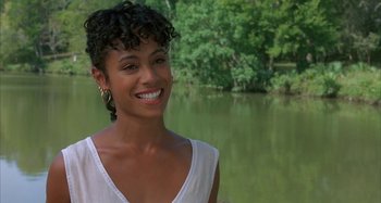 Movie still from “Jason's Lyric” (1994), directed by Doug McHenry – A woman smiling for the camera in front of a body of water; Close Up shot, Over the shoulder angle