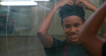 Movie still from “Jason's Lyric” (1994), directed by Doug McHenry – A woman in an apron holds her hair up in the air; Close Up shot, Over the shoulder angle
