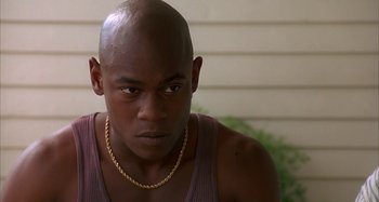Movie still from “Jason's Lyric” (1994), directed by Doug McHenry – A man with a gold chain around his neck looks to his left; Close Up shot, High angle