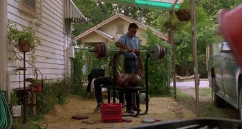 Movie still from “Jason's Lyric” (1994), directed by Doug McHenry – A man lifting a barbell in front of another man; Wide shot, Low angle