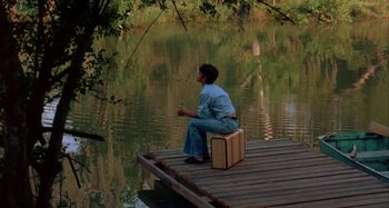 Movie still from “Jason's Lyric” (1994), directed by Doug McHenry – A woman sitting on a pier with a suitcase; Wide shot, High angle